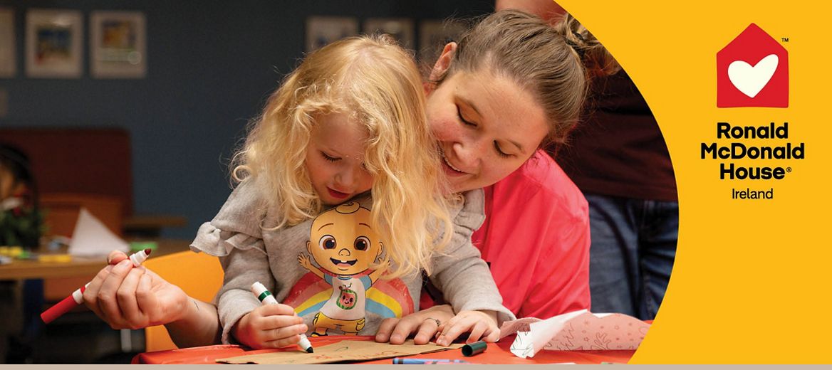 Mother and daughter colouring in togehter with the Ronald McDonlald House logo
