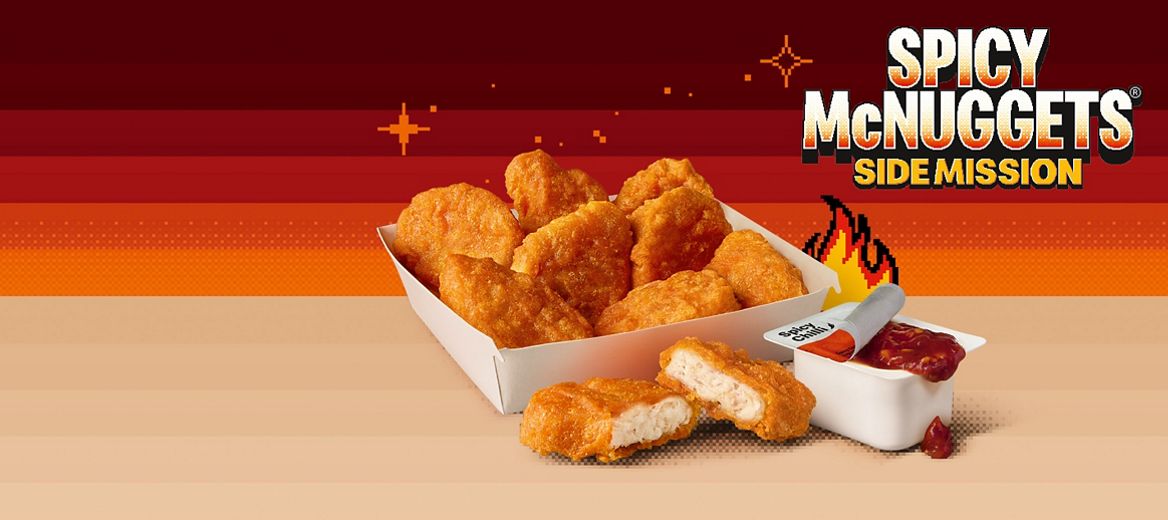 Spicy Chicken McNuggets and Spicy Chilli Dip on a brown shelf against a orange and red gradient pixelated background.