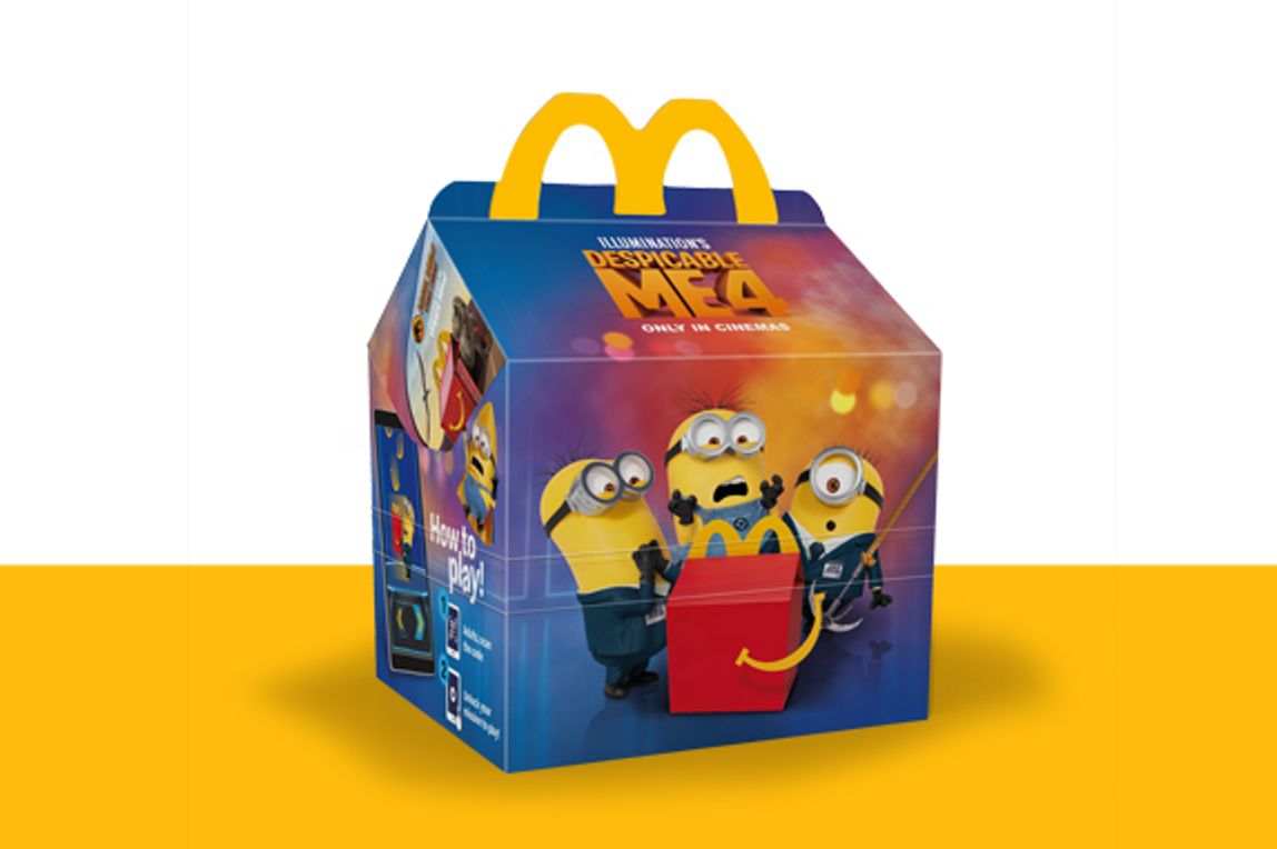 The Minion characters with a mixed purple background on a Happy Meal box on a yellow shelf.