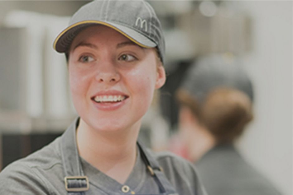 A young restaurant worker is smiling whilst on shift.