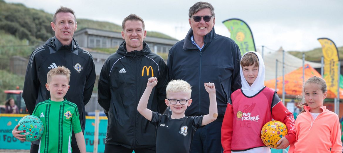 Kids at a Fun Football event on a pitch with a ball.