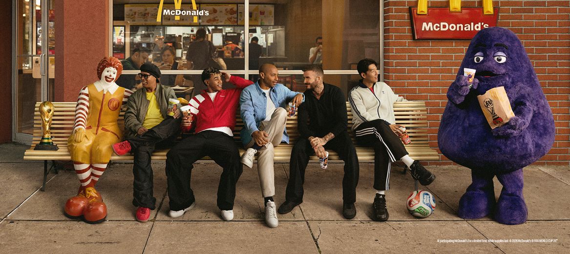 Grimace sitting on a bench with soccer stars