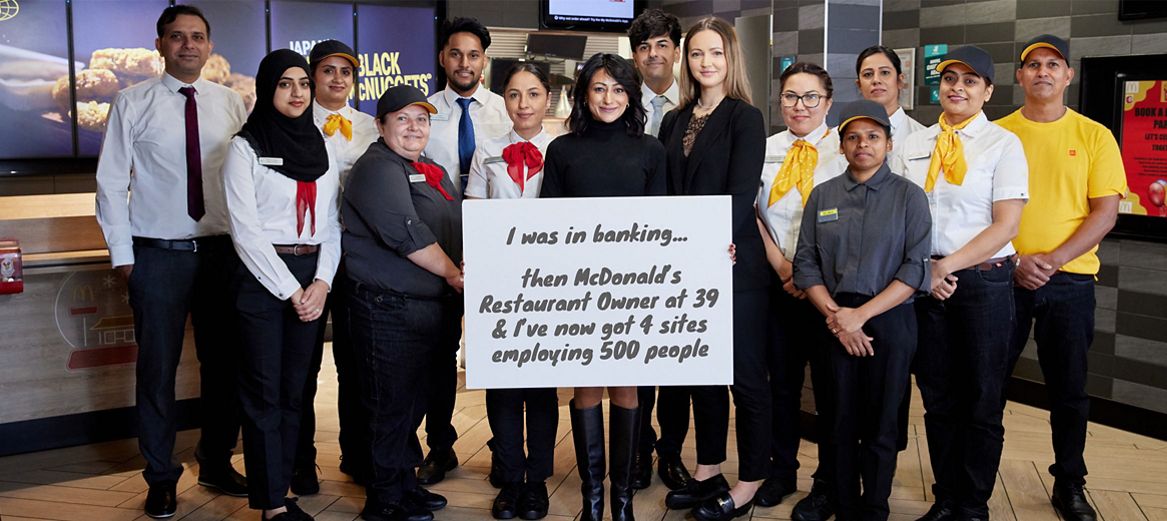 Franchisee Anisha Sharma with team in a McDonald’s restaurant holding a sign: ‘I was in banking… then McDonald’s Restaurant Owner at 39 & I’ve now got 4 sites employing 500 people