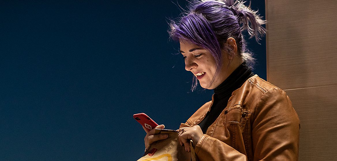 Woman smiling at phone holding a McDonald's bag