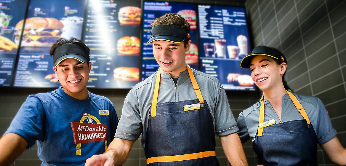 Three McDonald's employees smiling and working together