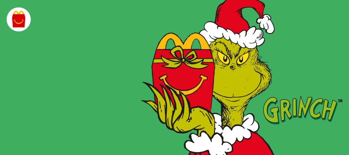 The Grinch wearing a Christmas hat holding a red Happy Meal box with a smile and a green bow