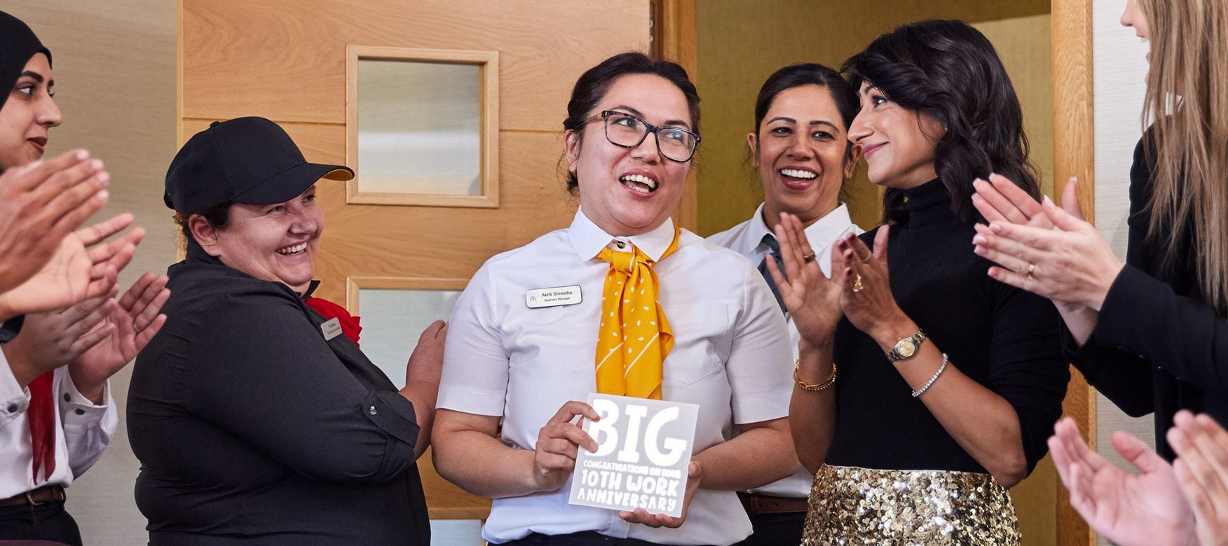 Franchisee with team celebrating an employee holding a sign reading: ‘BIG congratulations on your 10th work anniversary
