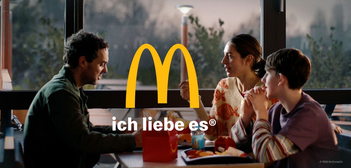 Vater, Mutter, Sohn sitzen an einem Tisch in einem McDonald’s Restaurant, essen Produkte eines Happy Meal's® und unterhalten sich in aufgelockerter Stimmung. Im Vordergrund das gelbe McDonald’s "M", darunter der Slogan "ich liebe es®"