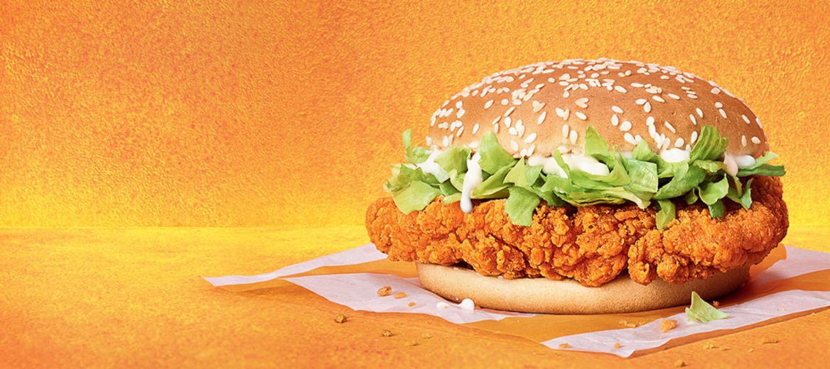 Crispy coated golden chicken breast, with crunchy lettuce and a creamy sauce, on a sesame seeded golden bun.