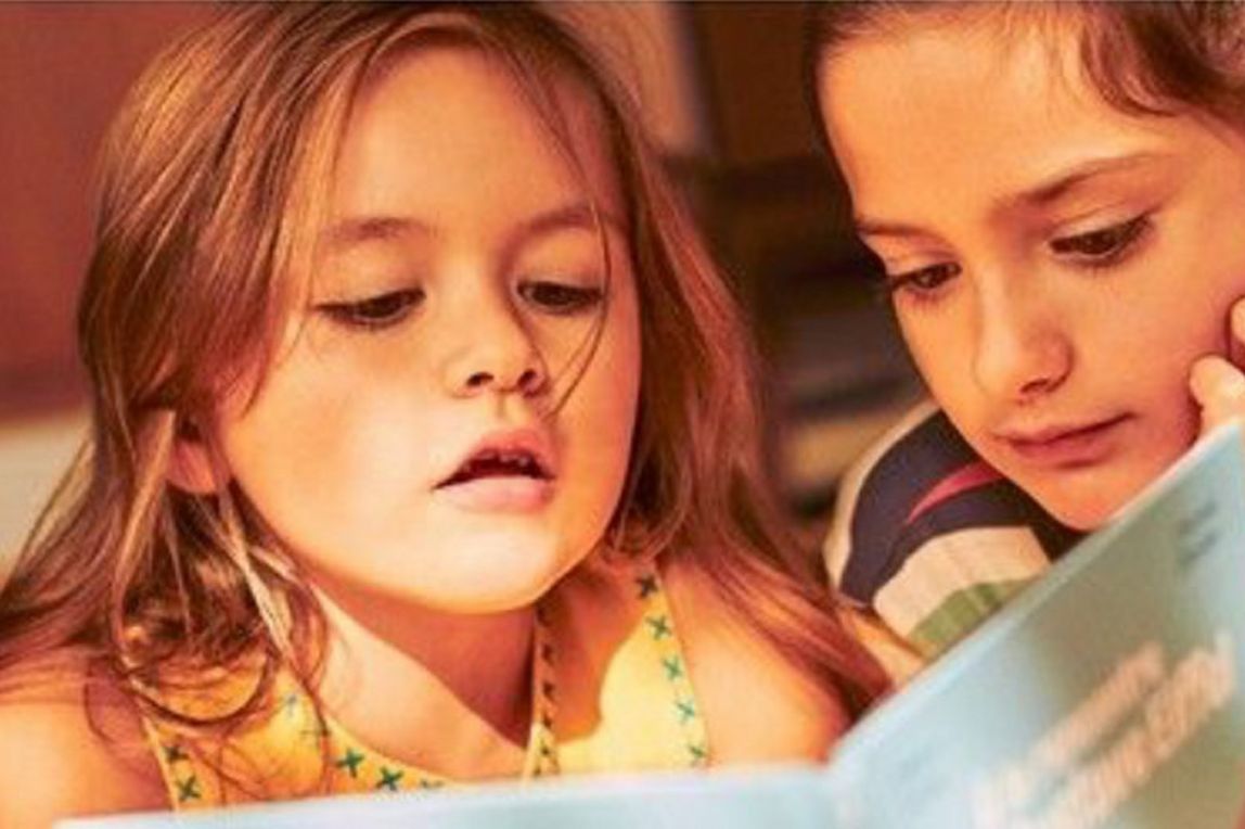 Two children reading a book together.