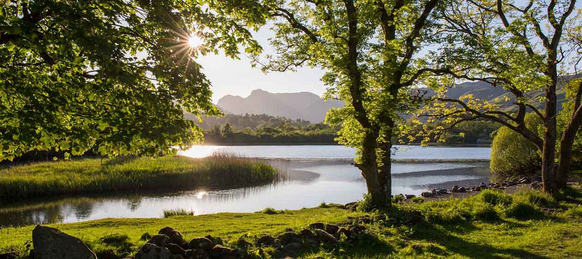 Beautiful countryside with a view of the sun shining on a lake.