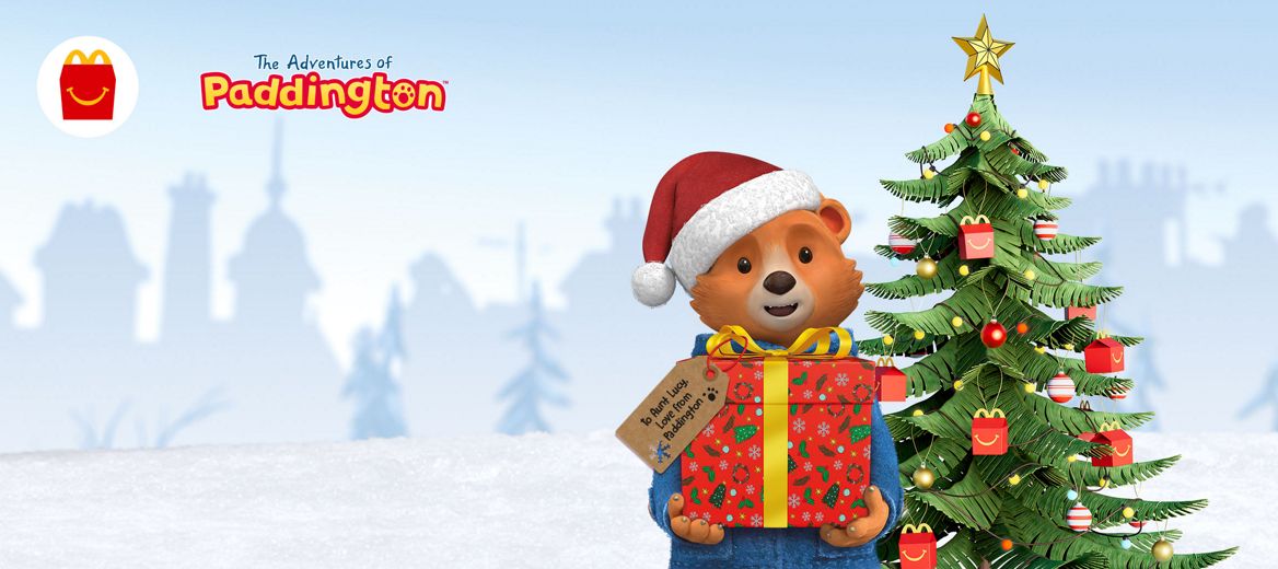 A frosty white background with Paddington Bear holding a wrapped gift.