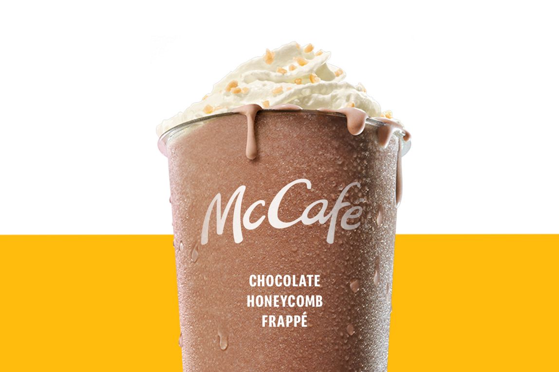 Chocolate Honeycomb Frappe topped with a swirl of whipped cream and honeycomb pieces set against a yellow and white background