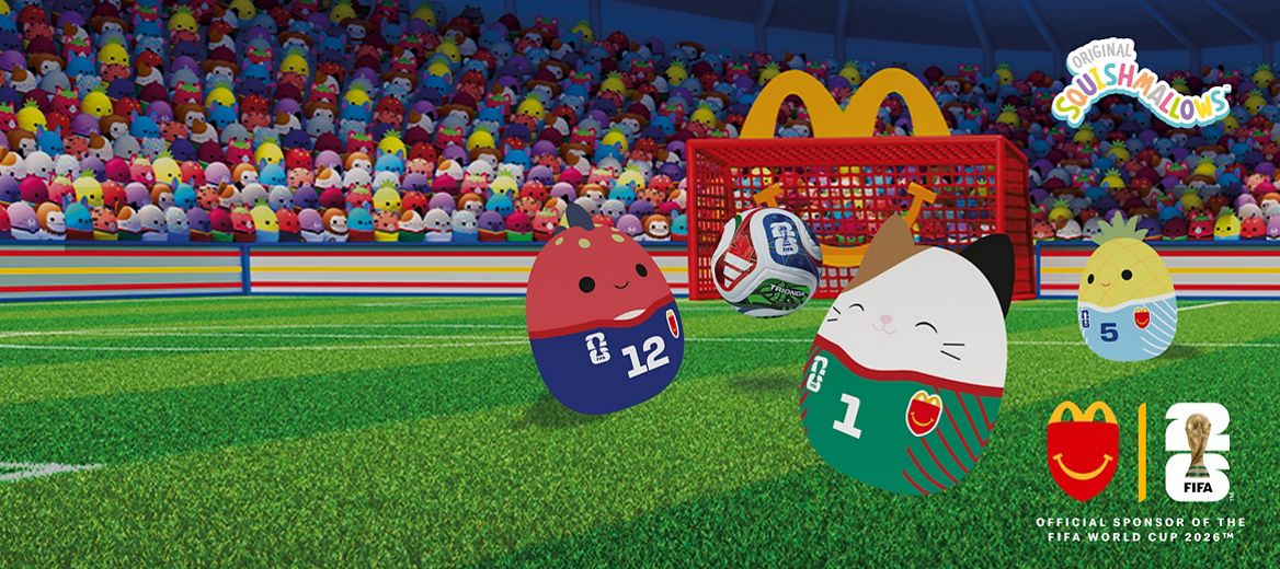 Squishmallows football characters on a pitch in front of a crowded stadium, with a ball mid-air and McDonald’s FIFA World Cup 2026 branding.
