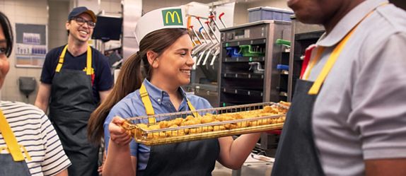 McDonald’s-Mitarbeiterin hält ein Tablett mit Chicken Nuggets in der Restaurantküche.