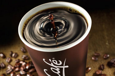 A McCafé Coffee cup surrounded by coffee beans