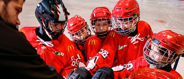 atoMc Hockey team huddling with coach before a game