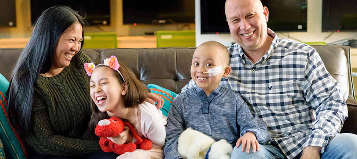 The Czyz RMHC family of four laughing together on a couch