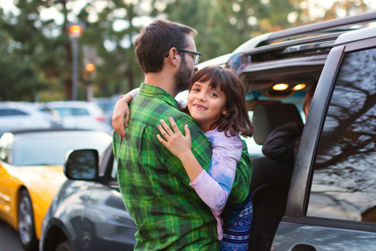 Father carrying daughter into car