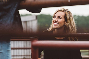 A woman with a pail in her arms smiling at another person in the distance