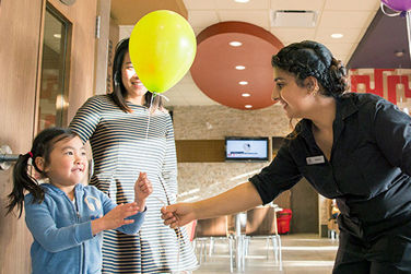 Le personnel de McDonald's remet un ballon jaune à une mère et à un enfant