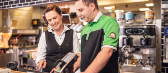 Eine McDonald's Store-Managerin zeigt einem Mitarbeiter das Kassensystem