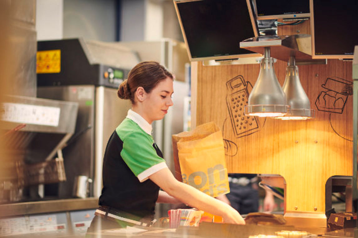 Eine McDonald's Mitarbeiterin füllt eine Papiertüte mit einer Bestellung