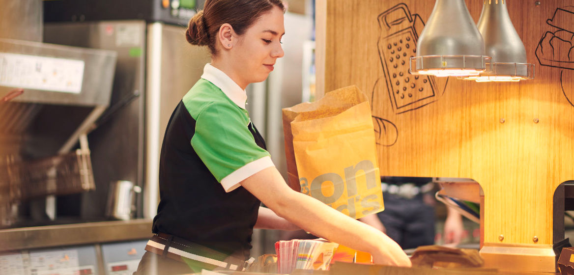 Eine McDonald's Mitarbeiterin füllt eine Papiertüte mit einer Bestellung