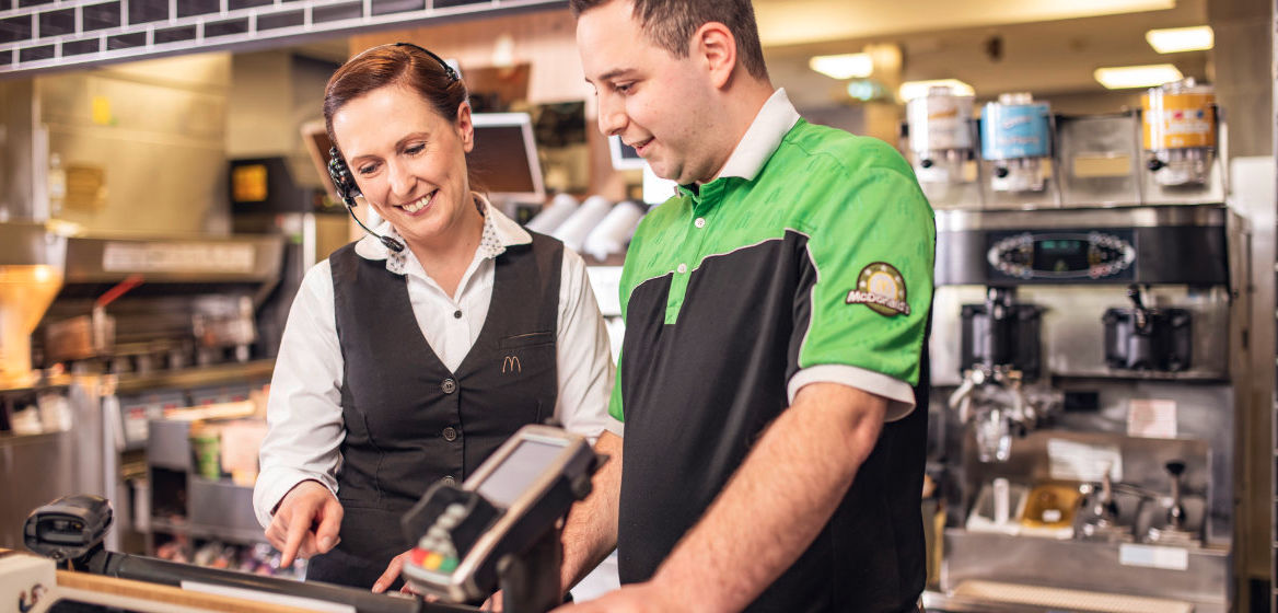 Eine Restaurant Managerin zeigt einem McDonald's Mitarbeiter das Kassensystem