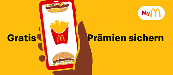 Im Vordergrund eine Hand, die ein Smartphone hält, auf dem die McDonald’s App geöffnet ist. Im Hintergrund der Hinweis zum Bonusprogramm MyMcDonald’s und der Aussage „Gratis Prämien sichern“.