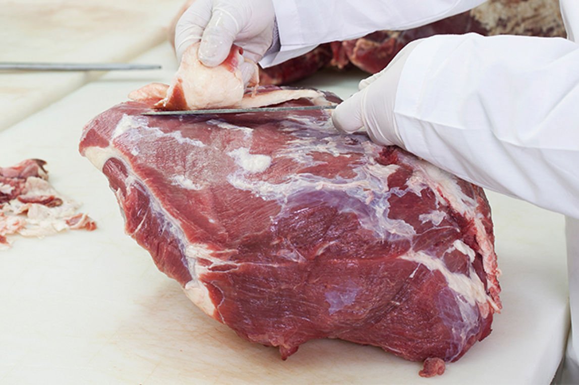 Von einem Stück Rindfleisch wird eine Scheibe heruntergeschnitten.