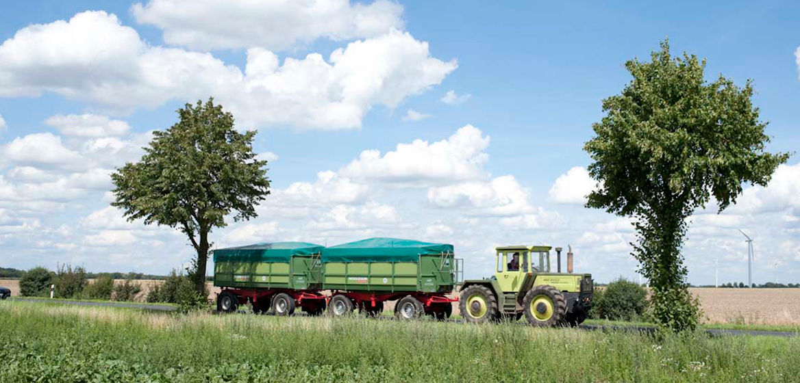 Traktor mit zwei Anhängern auf einer Landstraße