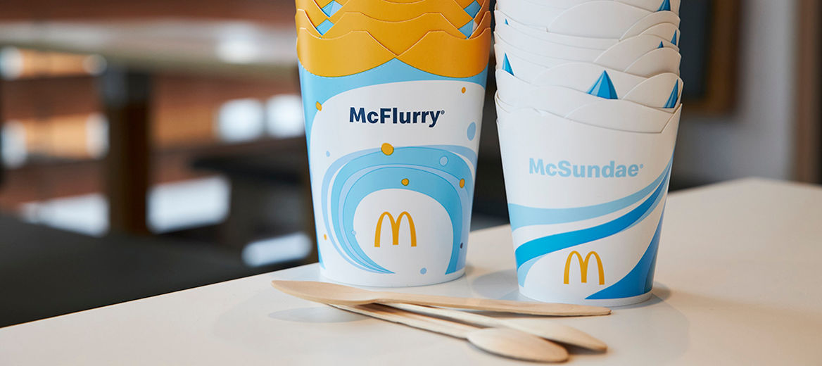 Holzlöffel vor gestapelten McFlurry®- und McSundae®-Bechern