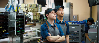 Two McDonald's staff member reading an incoming order on a tv monitor