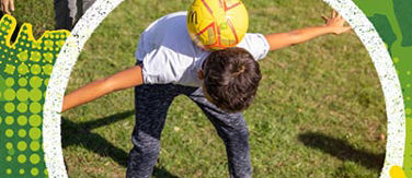 Boy at McDonald’s Fun Football session  practicing how to balance the ball on a pitch