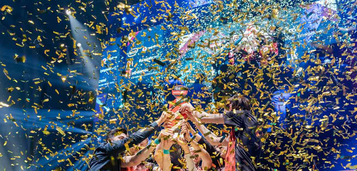 E-Sportler stemmen im goldenen Konfetti regen den Pokal der ESL-Meisterschaft in die Höheiner Bühne und halten McDonald's-Becher