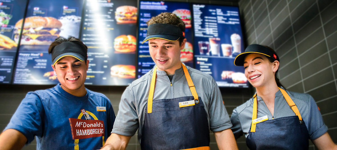 Three McDonald's employees smiling and working together