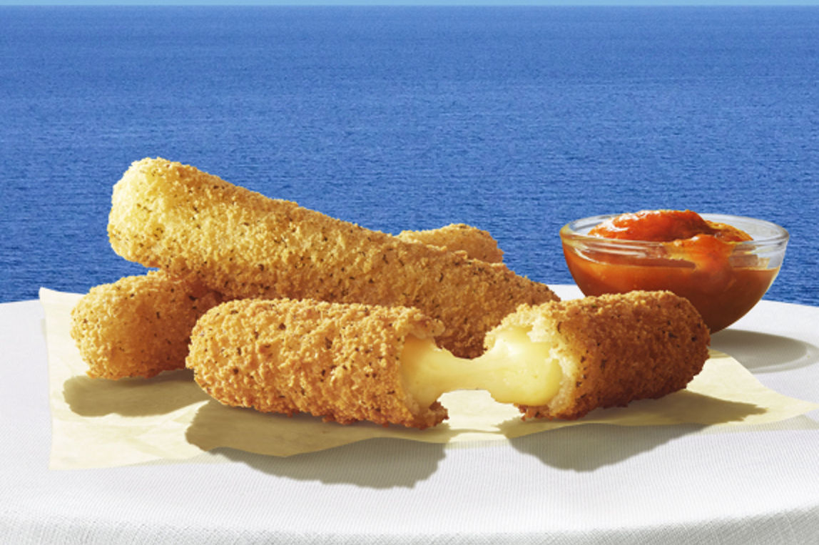 A trio of Mozerella dippers, one torn in half to reveal oozing cheese, with a pot of salsa dip on a white tablecloth in front of a seascape background.