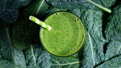 Green smoothie in a glass with a green and white striped straw