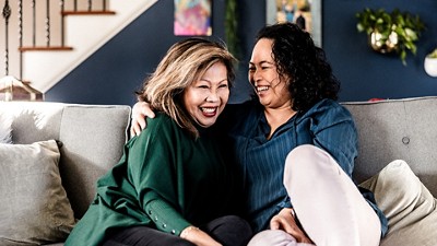 Mother and daughter sitting on a couch smiling and talking