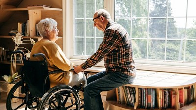 Older woman in a wheelchair with her husband  looking out a window