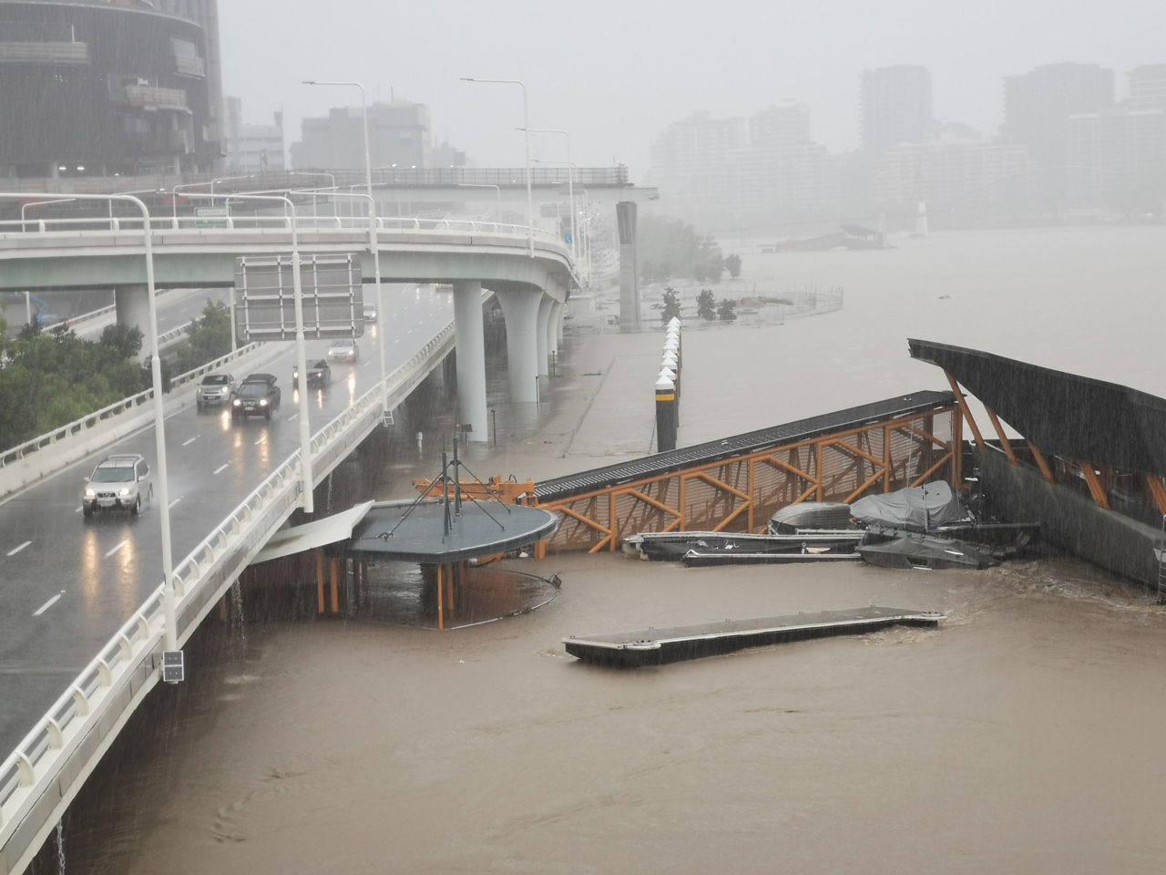 Brisbane, Australia - February 27, 2022: Wild weather and heavy rain falls from Tropical Cyclone storm Brisbane Central Business District. The North Quay ferry terminal is flooded and closed. Brisbane river is overflowing.