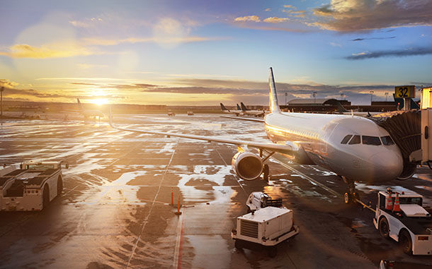 Airplane being preparing for takeoff at terminal gate in international airport at sunrise