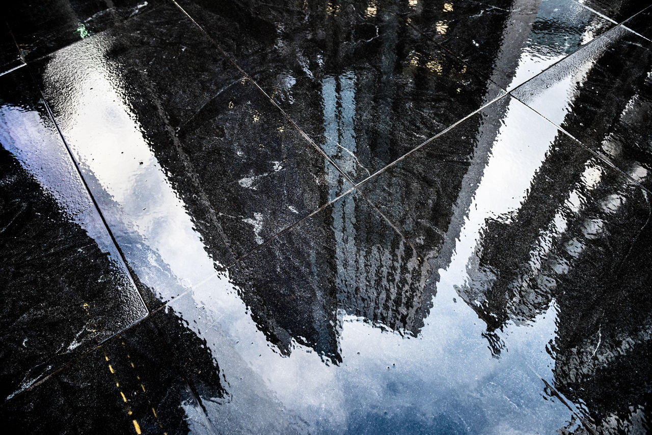 Reflections in the wet sidewalk of modern office skyscrapers in City of London.