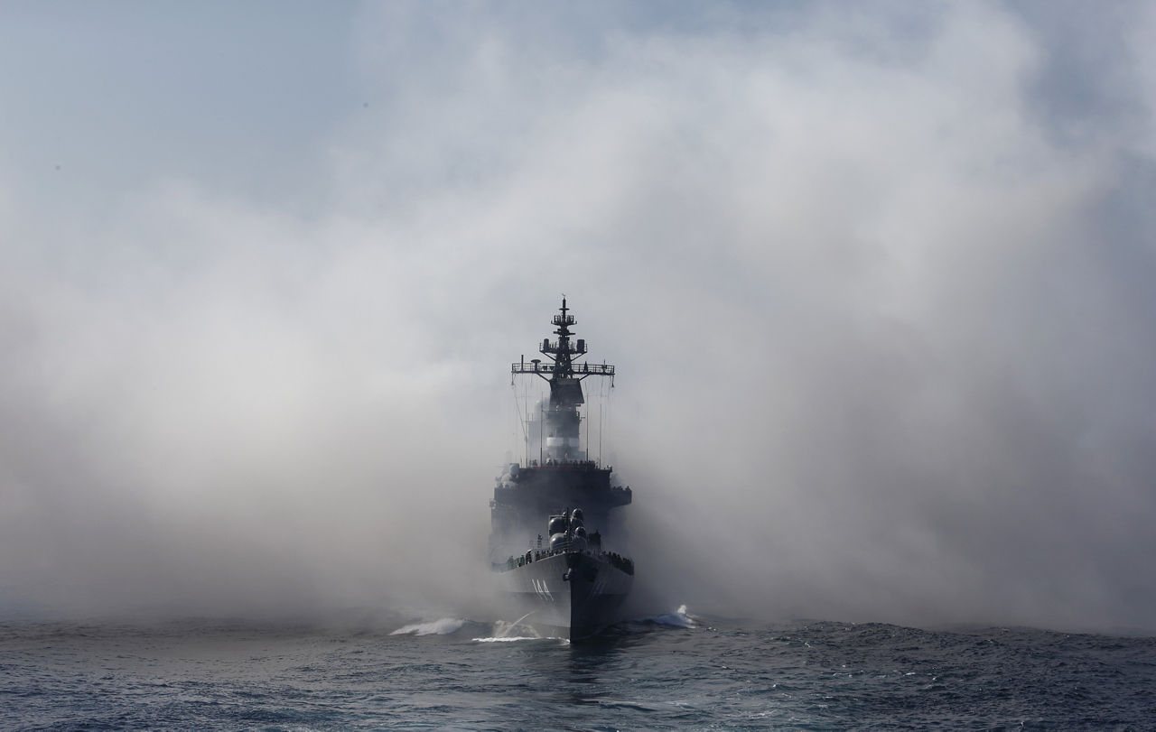 Japan's Maritime Self-Defense Force destroyer ship Kurama sails through the smoke of anti-IR missile flares during a review at Sagami Bay, off Yokosuka, Kanagawa Prefecture, Japan. Photographer: Tomohiro Ohsumi/Bloomberg