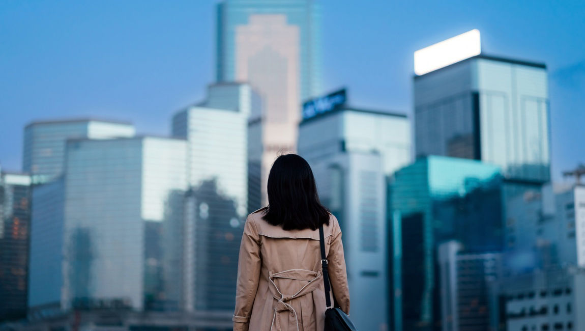 Woman wearing trench coat looking at skyscrapers