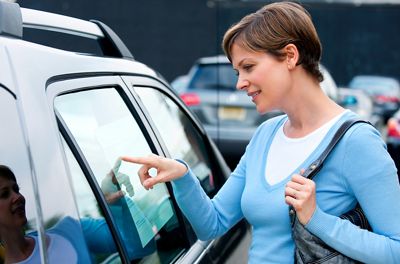 Woman checking out prices on cars at a dealer's car lot.