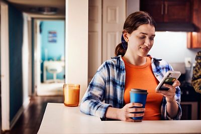 Young woman on cell phone in her apartment kitchen