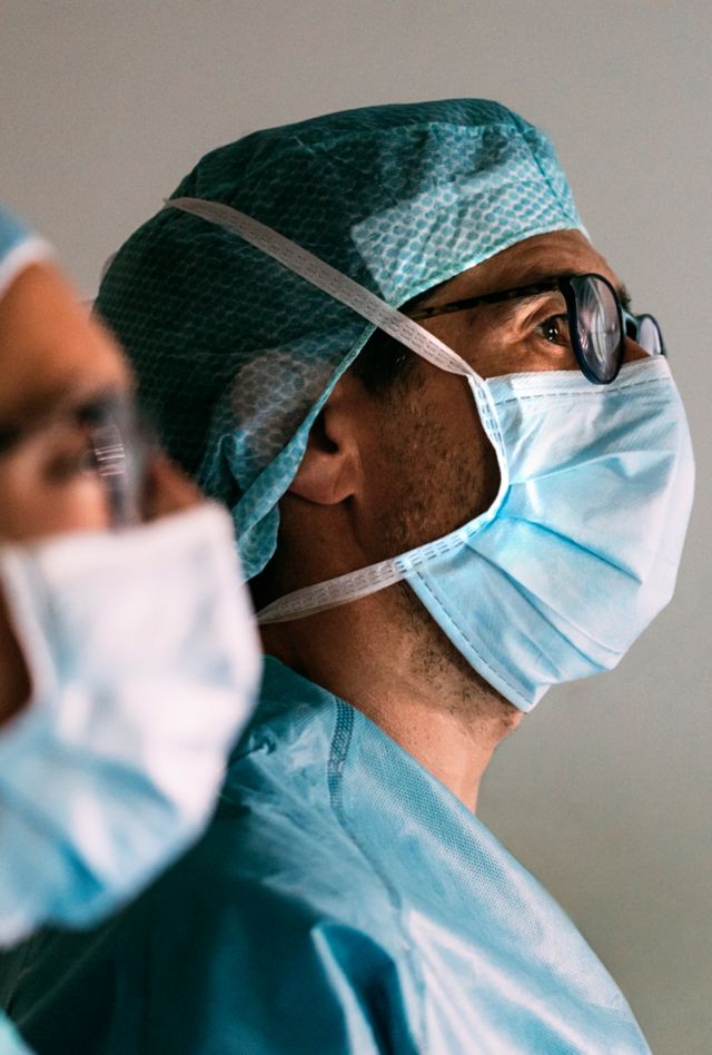 Profile view of two health care workers wearing masks and scrubs