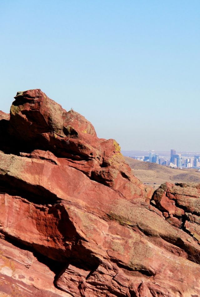 A city sits in the distance behind a rock formation.